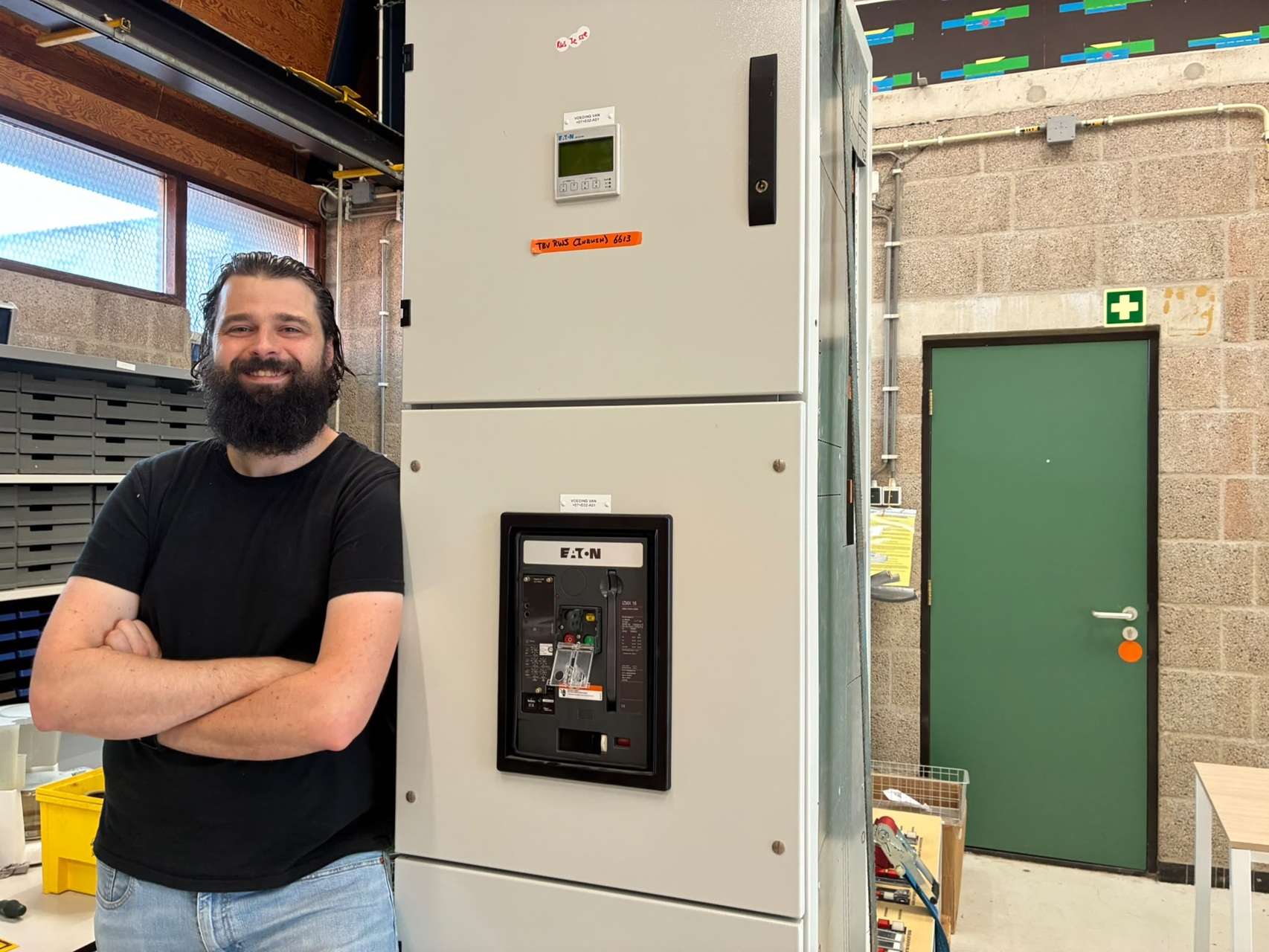 Objectdeskundige Jesse Loomans staat naast een laagspanningskast die door Rijkswaterstaat wordt overgedragen aan Normec Inrush voor praktijkonderwijs.