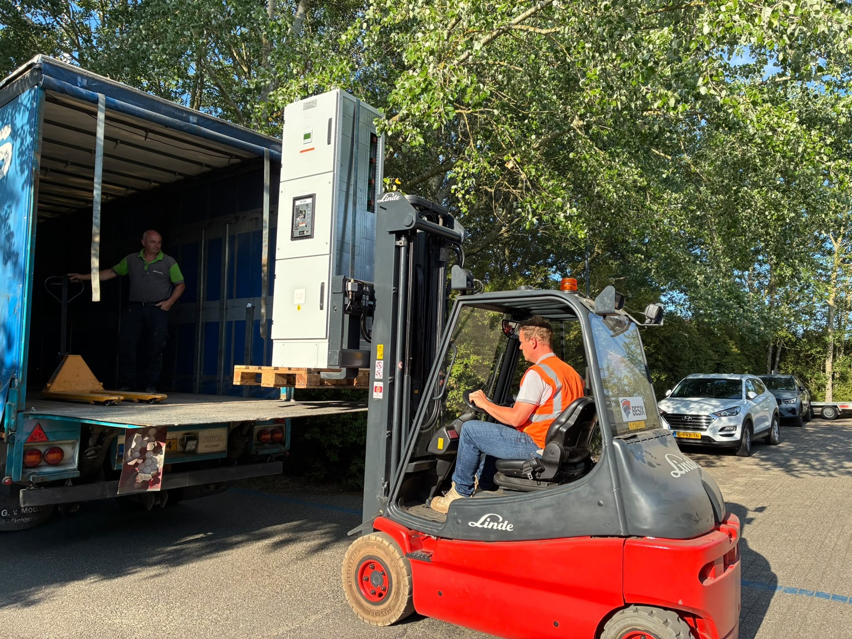 Een heftruck laadt onderdelen van een laagspanningskast in een vrachtwagen voor transport naar de praktijklocatie van Normec Inrush.